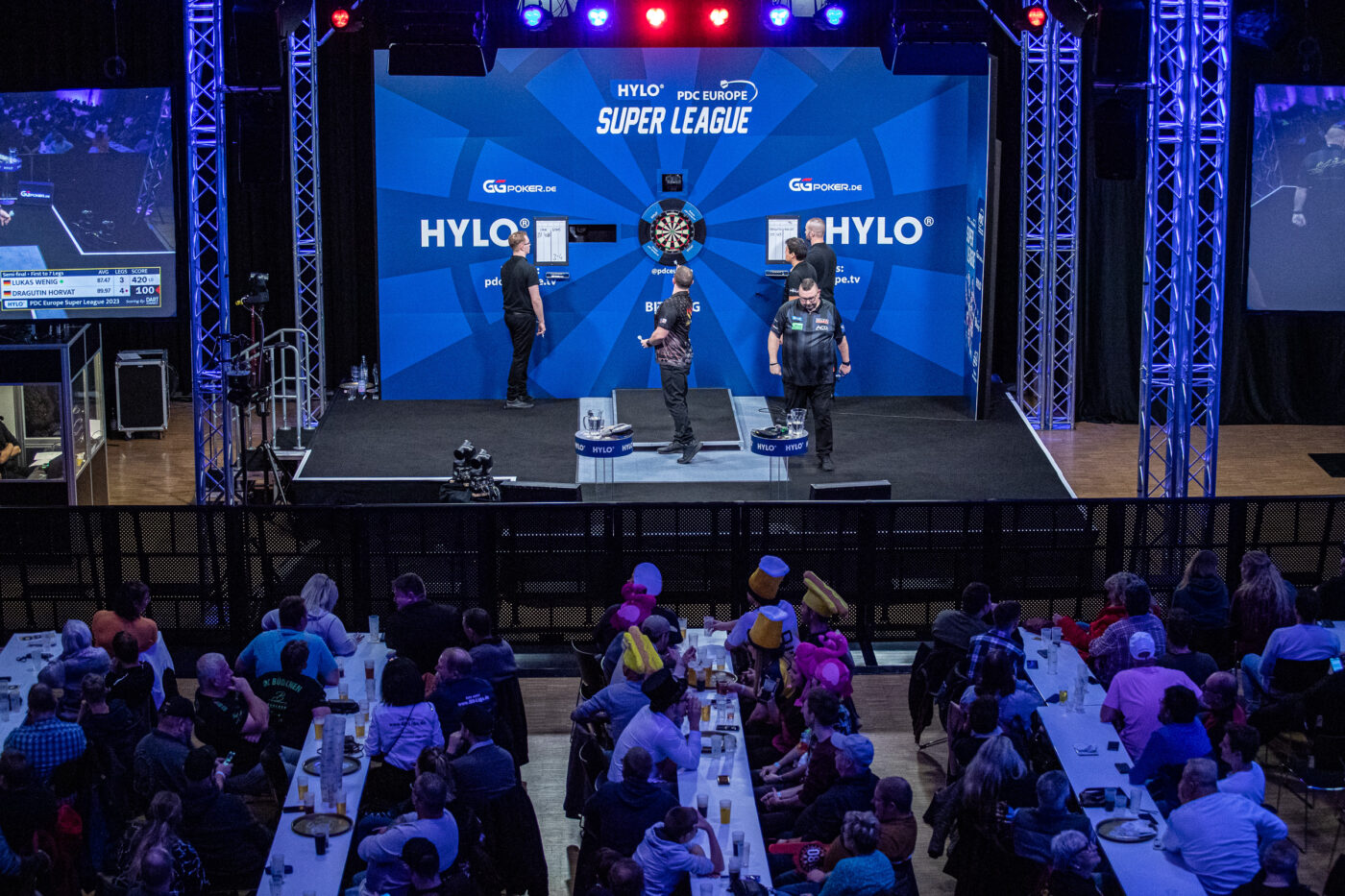 Bühne der HYLO PDC Europe Super League und verkleidete Zuschauer, die das laufende Spiel verfolgen