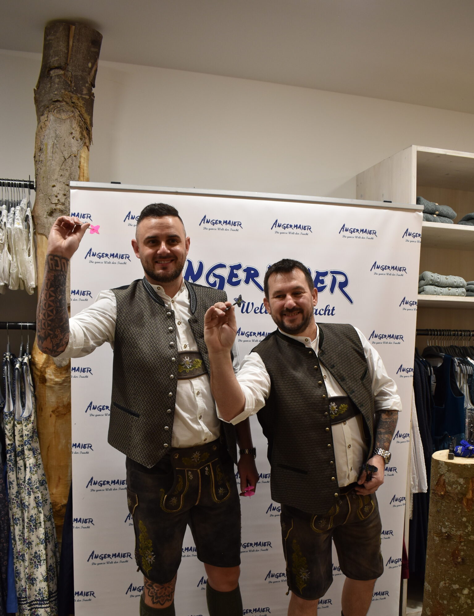 Joe Cullen und Jonny Clayton posieren mit Dartpfeilen in der Hand in Tracht im Angermaier.