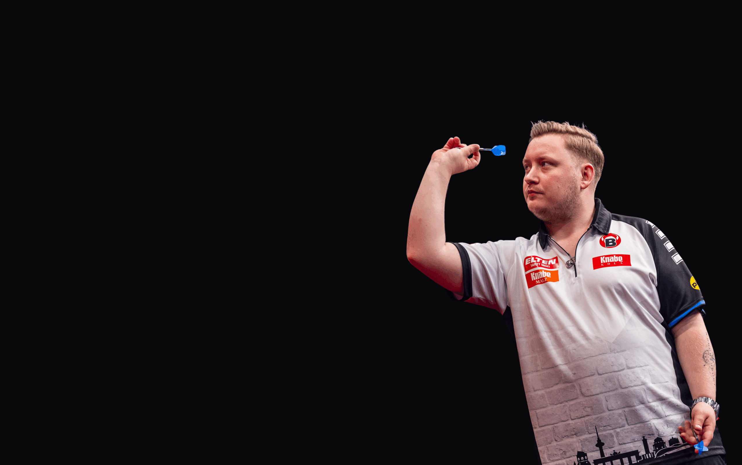 Nahaufnahme von Martin Schindler während einer Aufnahme mit Dartpfeil in der rechten Hand und konzentriertem Blick nach vorne