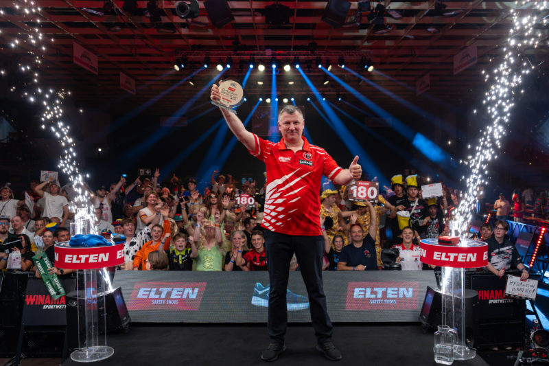 Krzysztof Ratajski triumphiert in Leverkusen bei den European Darts Open 2026 und streckt die Siegestrophäe vor jubelndem Publikum mit dem Arm hoch.
