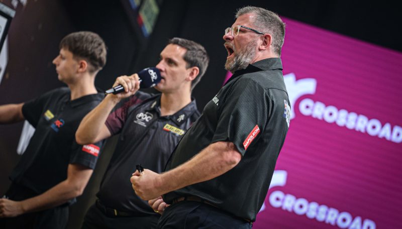 James Wade jubelt nach Sieg der Flanders Darts Trophy 2026, im Hintergrund Caller Charlie Corstorphine